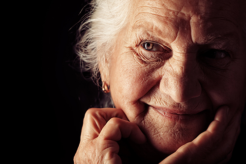 Close up of elderly woman with bright brown eyes in dim lighting 